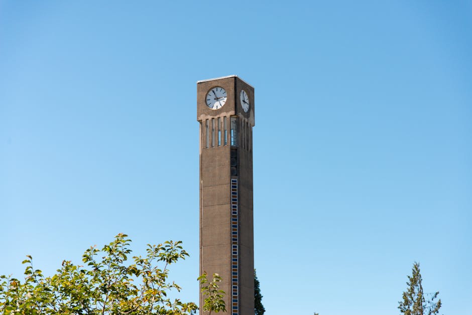 A tall clock tower stands against a clear blue sky on the UBC Vancouver campus.