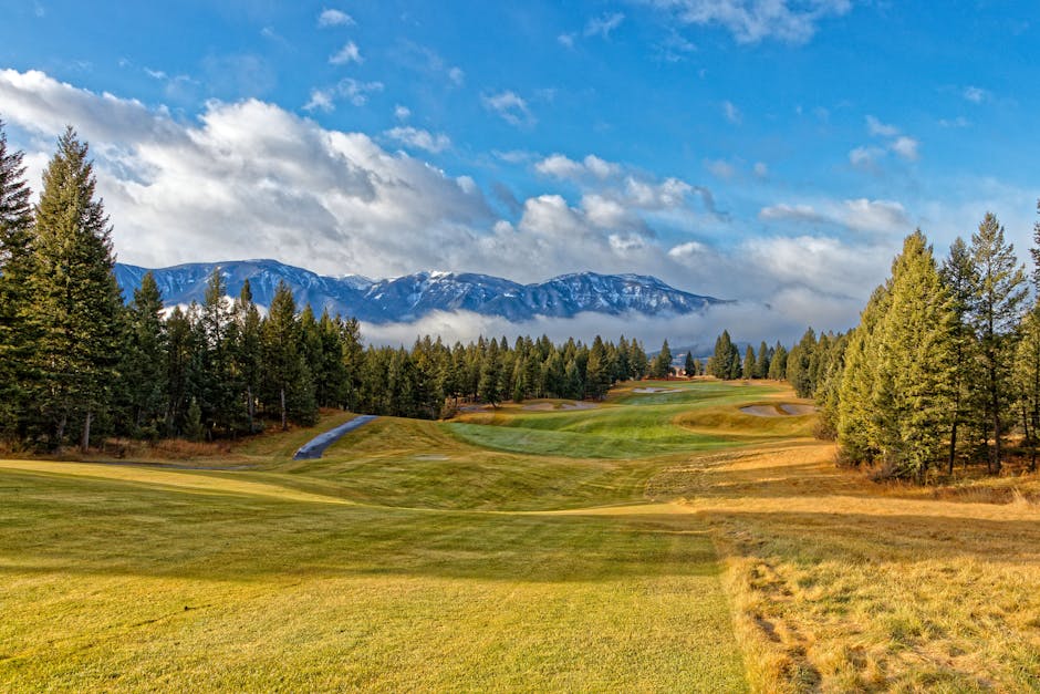 Lush golf course in Invermere, British Columbia with stunning mountain backdrop and evergreen trees.