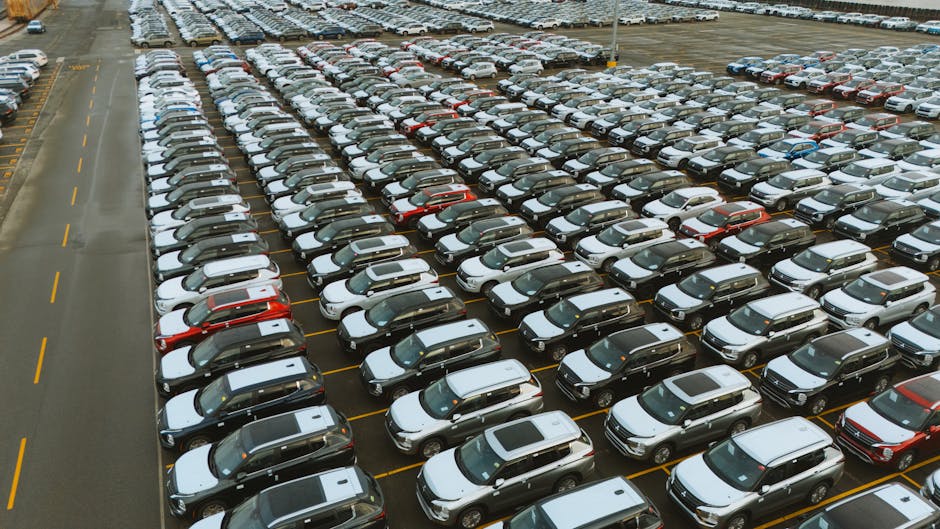 Aerial shot of an extensive car parking lot filled with new vehicles ready for distribution.