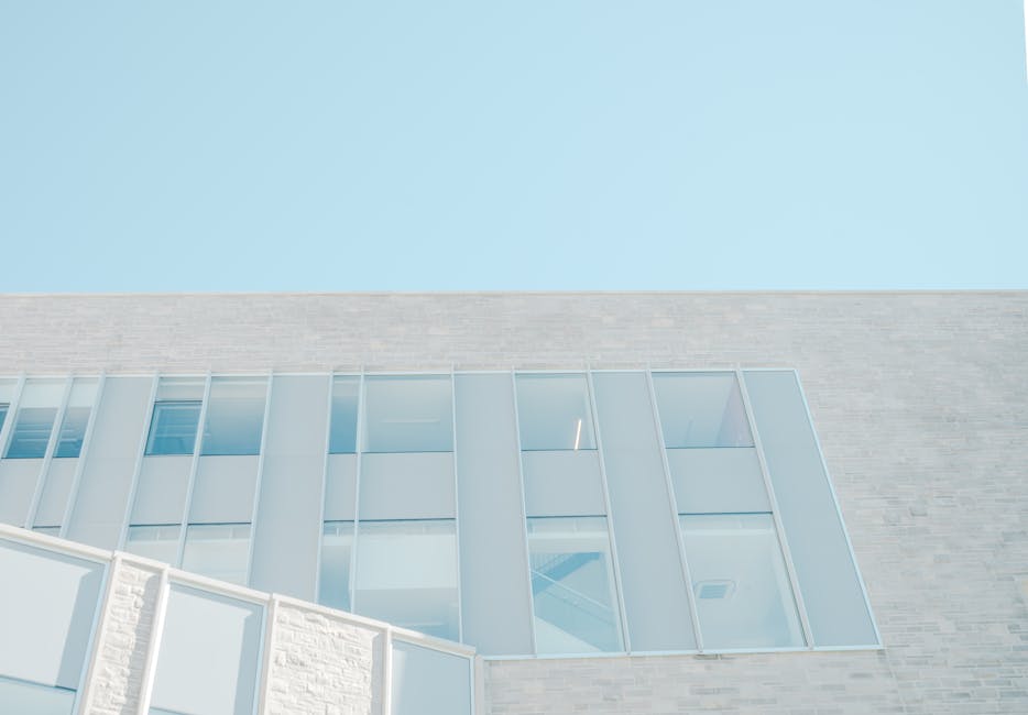 Low angle view of a modern glass facade against a bright blue sky in London, Ontario.