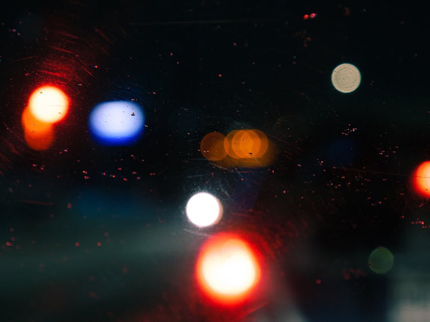 Blurred city lights through a car windshield at night creating an artistic abstract pattern.