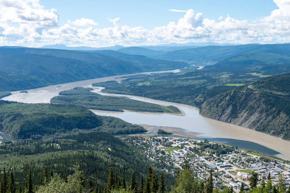 A breathtaking aerial shot of Dawson City, Yukon, Canada with the scenic Yukon River winding through lush green valleys.