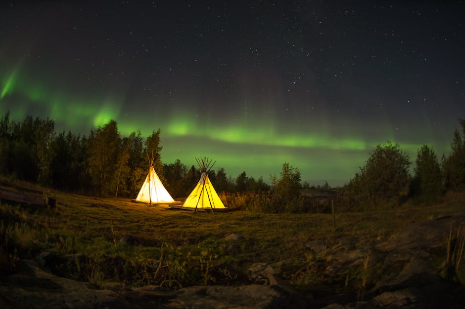 Gorgeous aurora borealis lighting up a tranquil campsite in Yellowknife, Canada, with starry sky.